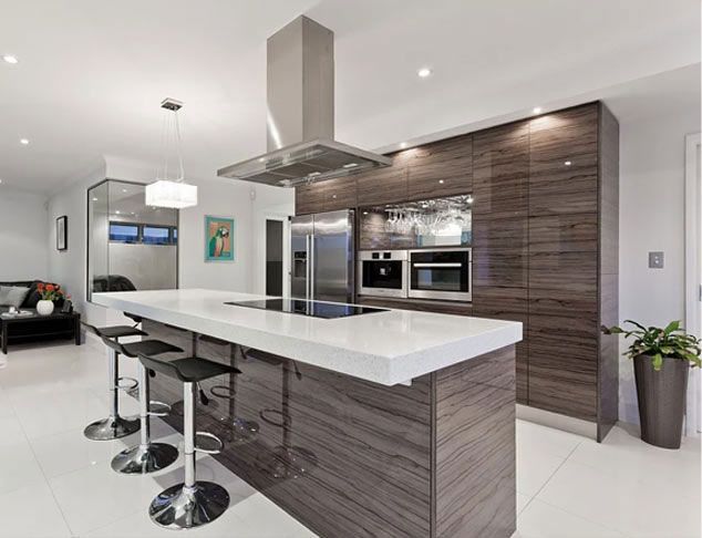 Modern kitchen with dark wood cabinetry, white countertop island with bar stools, stainless steel appliances, and recessed lighting.
