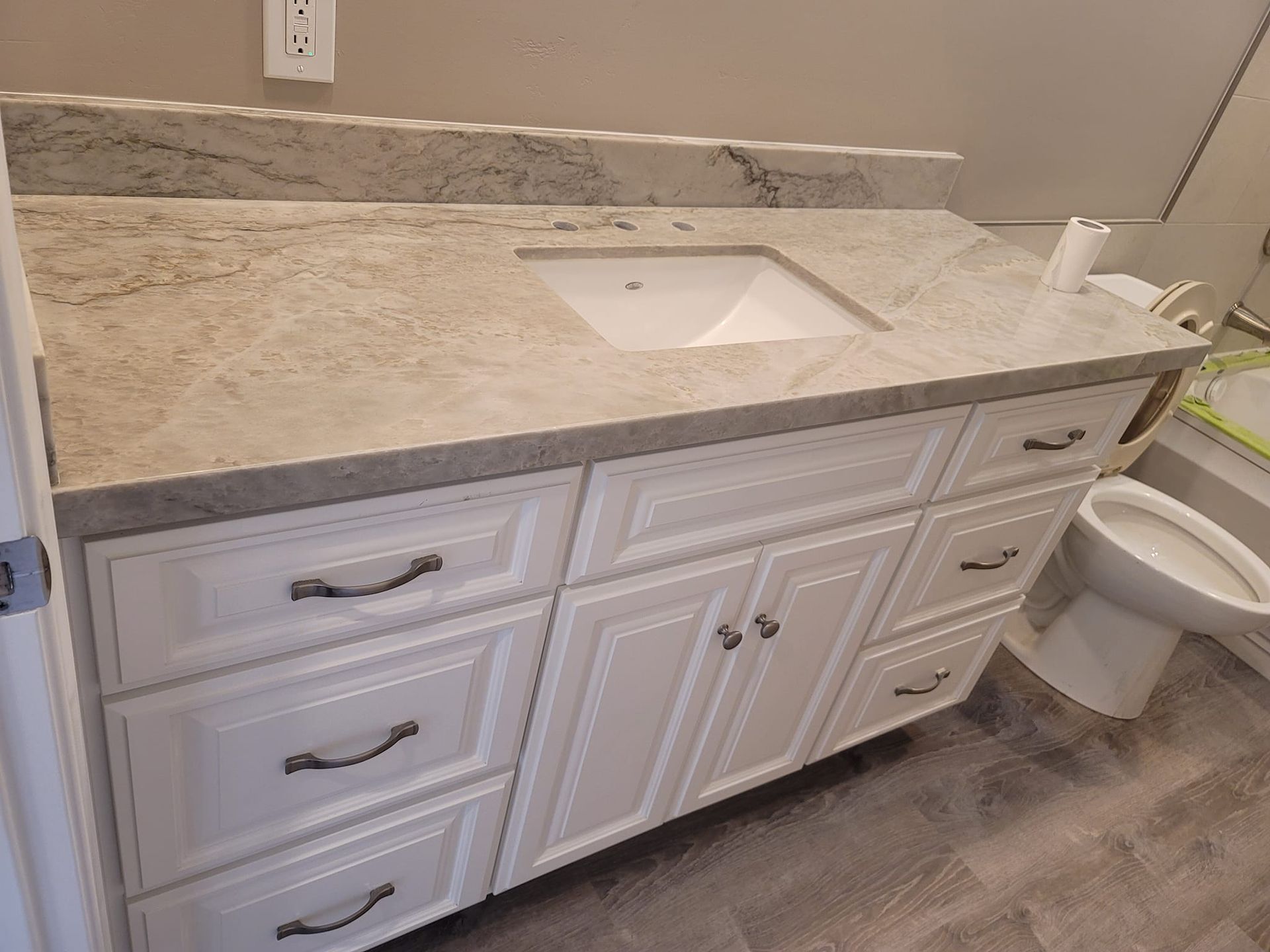 White bathroom vanity with a light-colored countertop and a built-in sink. A toilet is to the right.