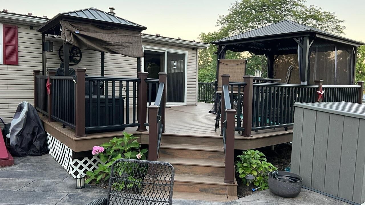 A mobile home with a deck and gazebo in front of it.