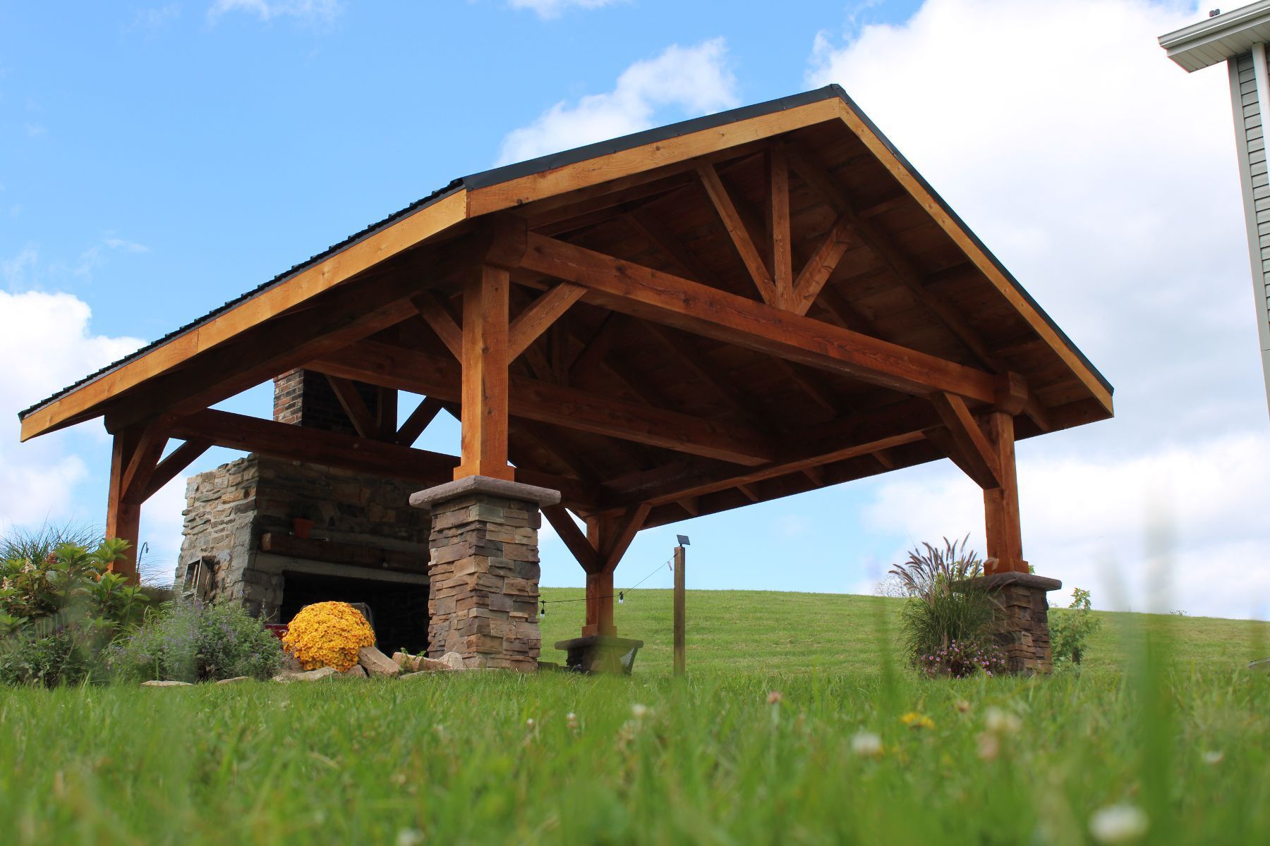 A wooden pavilion with a fireplace in the middle of a grassy field