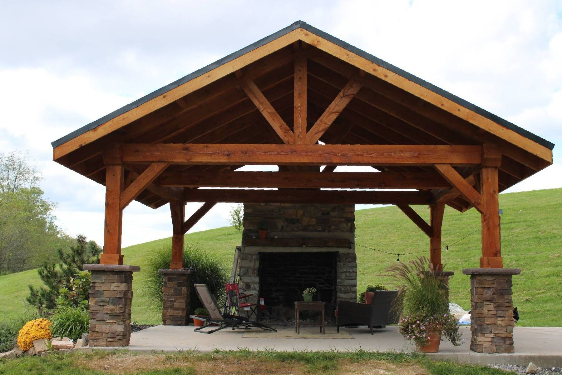 A wooden pavilion with a fireplace in the middle