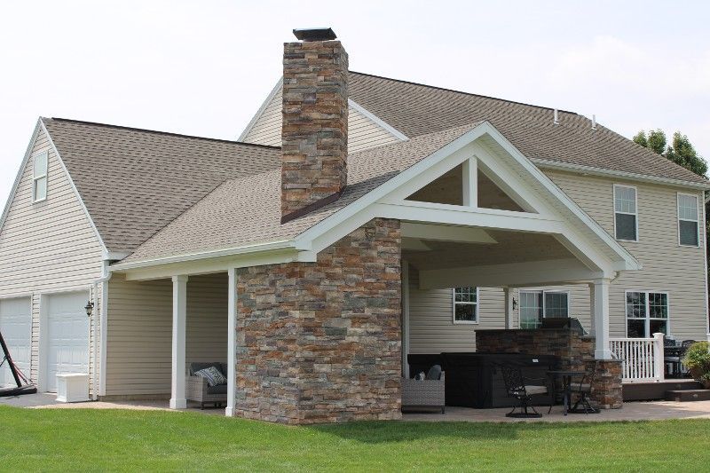 A house with a covered porch and a stone chimney