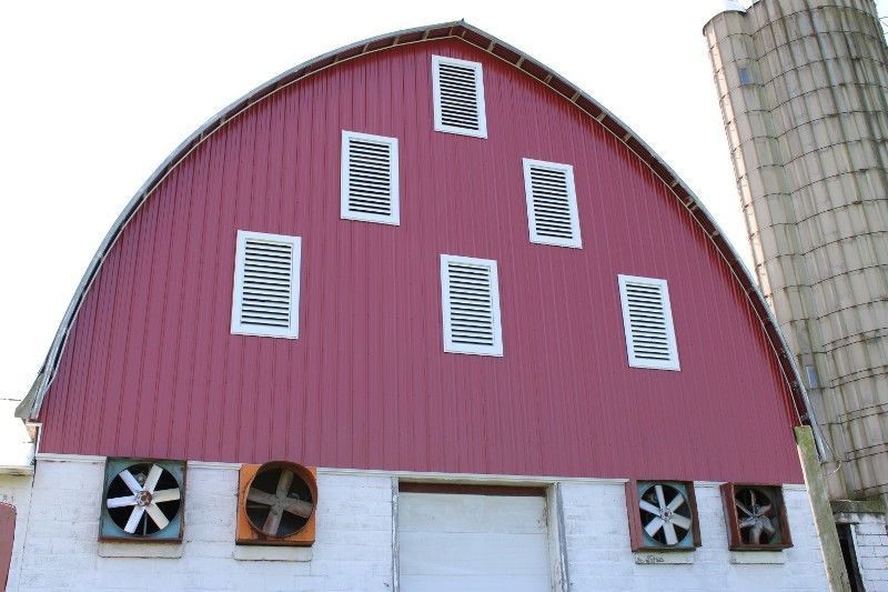A red and white barn with silos in the background