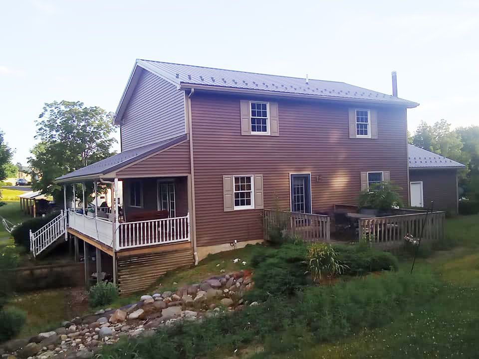 A large brown house with a large porch and stairs