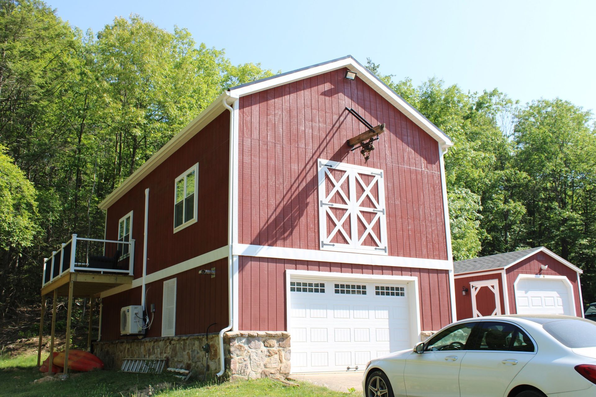 A red barn with a white car parked in front of it.