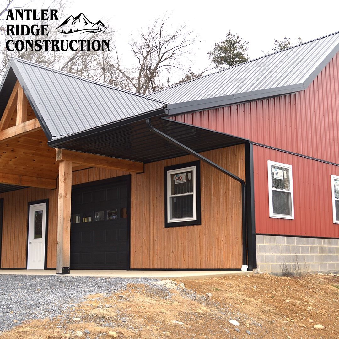 A red barn with a black roof and a wooden porch.