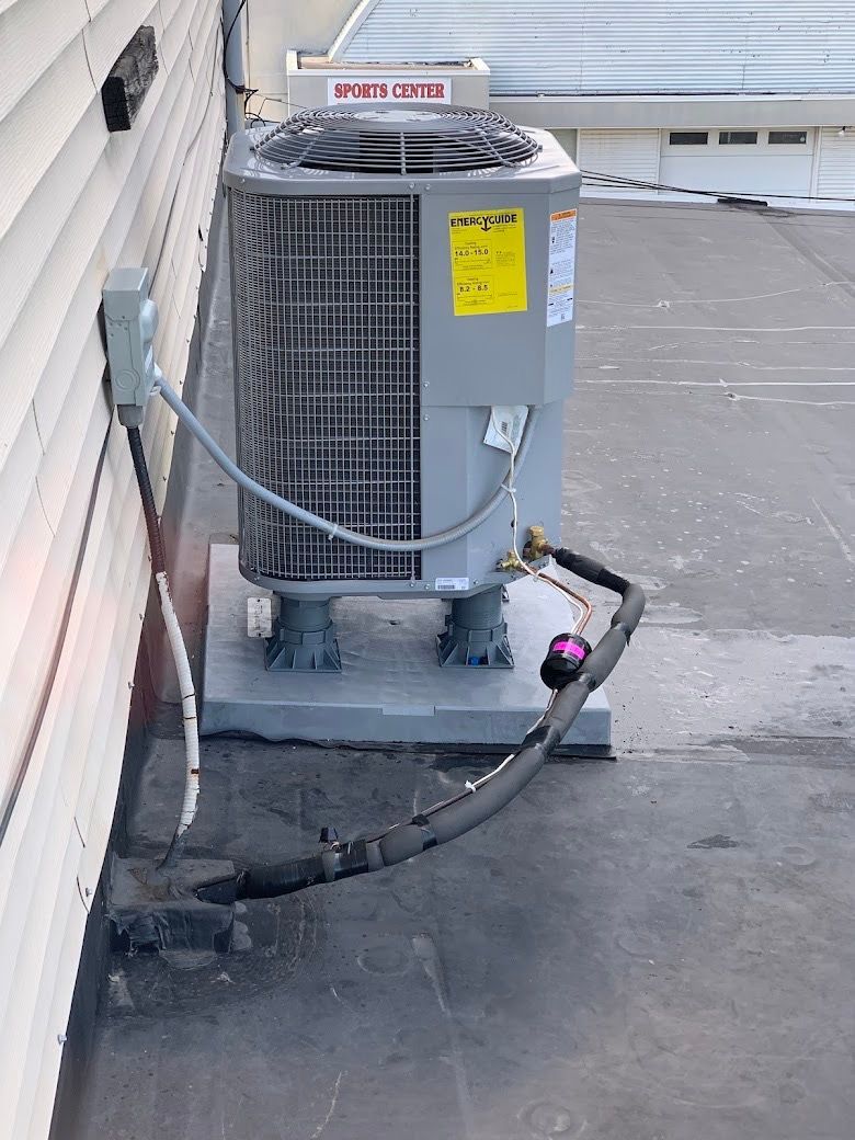 An air conditioner is sitting on top of a roof next to a wall.