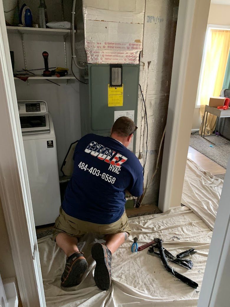 A man is kneeling on the floor in a laundry room working on an air conditioner.