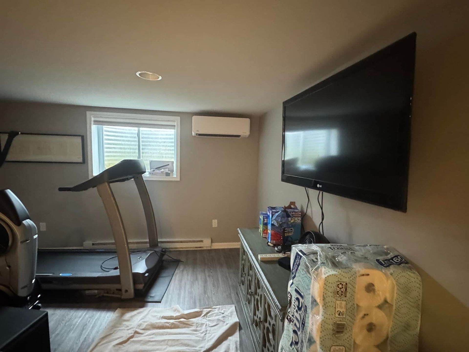 A home gym with a treadmill and a flat screen tv.