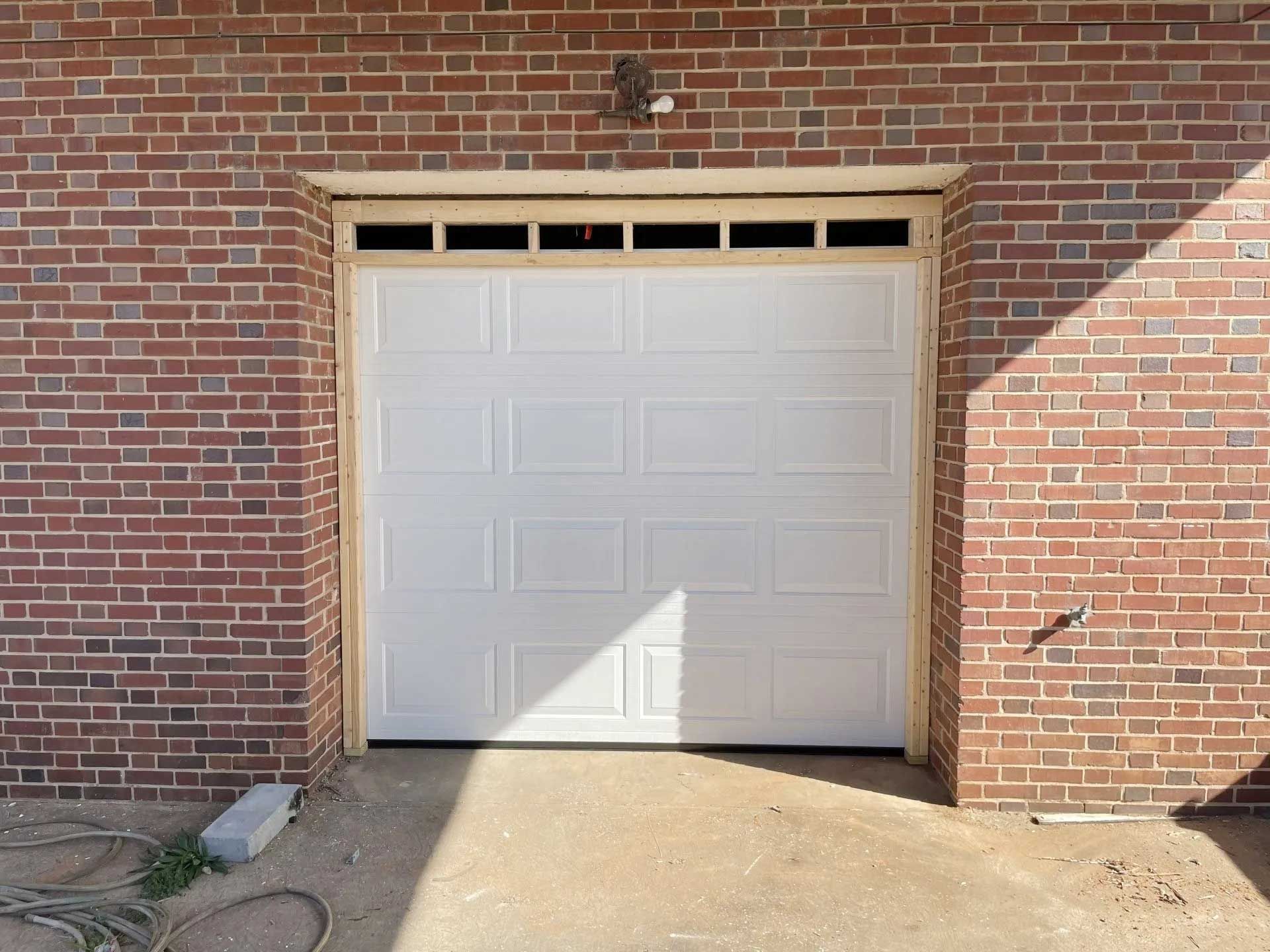 White garage door set in brick wall.