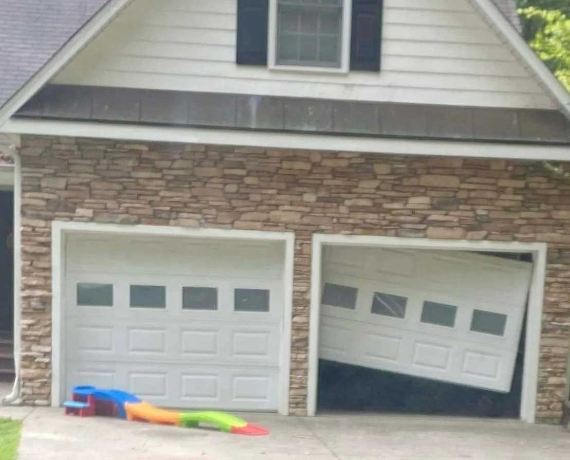 Garage with one door ajar at an angle. A child’s toy is in front of the left door.
