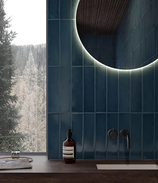 A bathroom with blue tiles and a round mirror