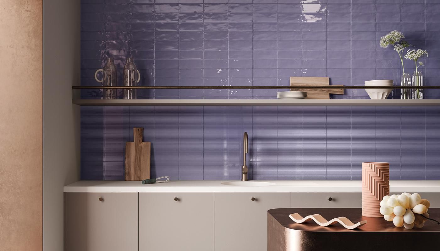 A kitchen with purple tiles on the wall and a sink.