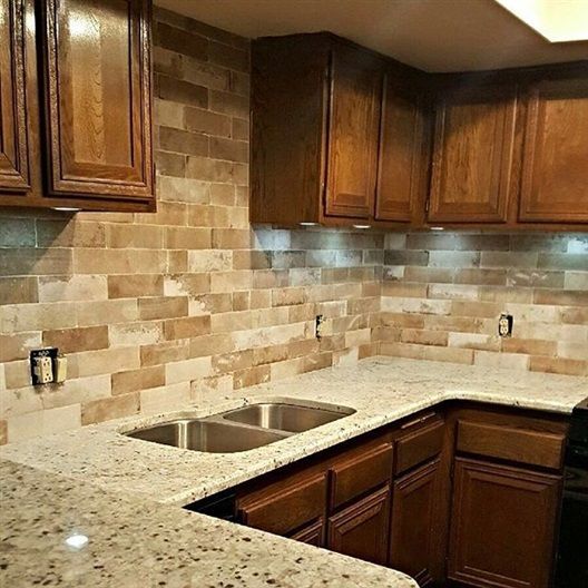 A kitchen with two sinks , granite counter tops , and wooden cabinets.