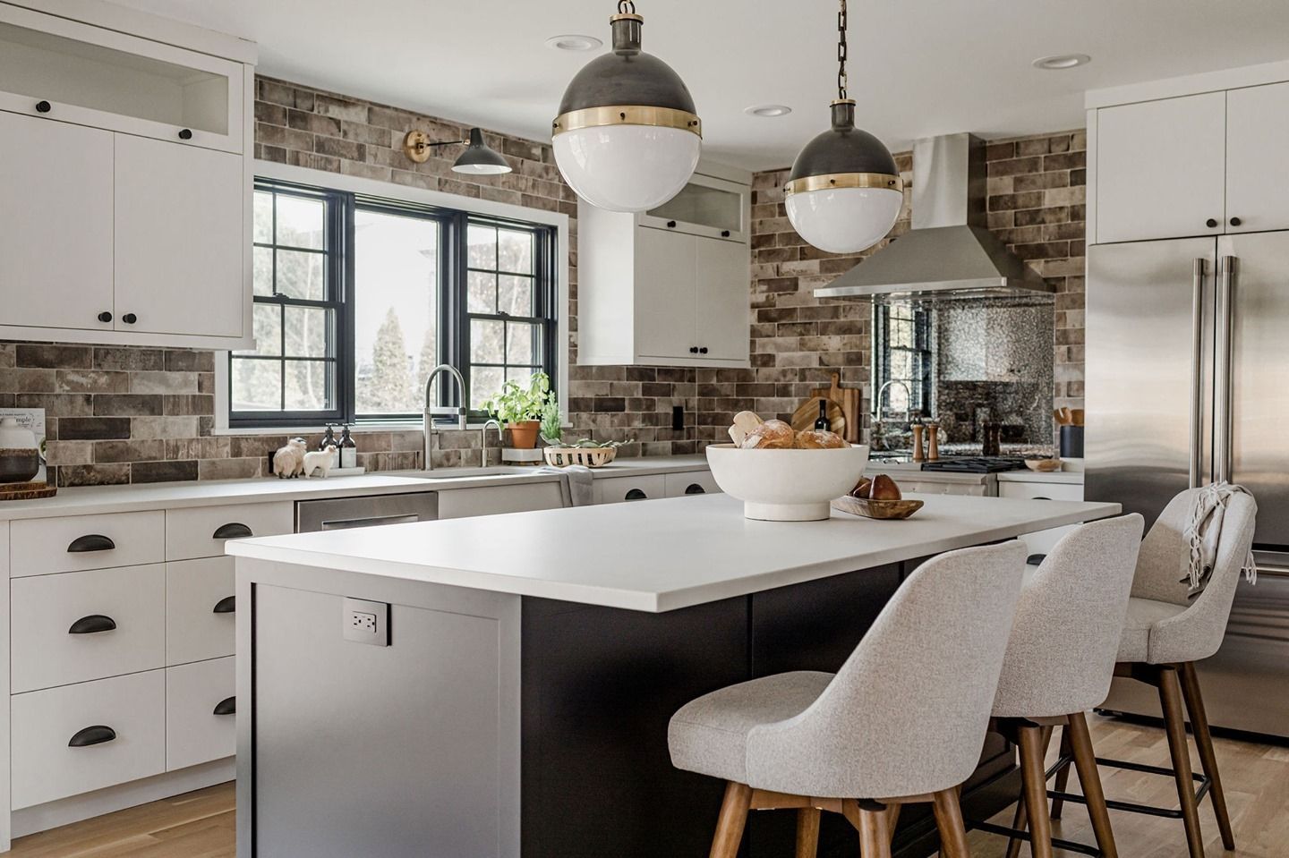 A kitchen with white cabinets , stainless steel appliances , and a large island.