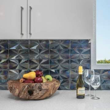 There is a bowl of fruit and a bottle of wine on the counter.