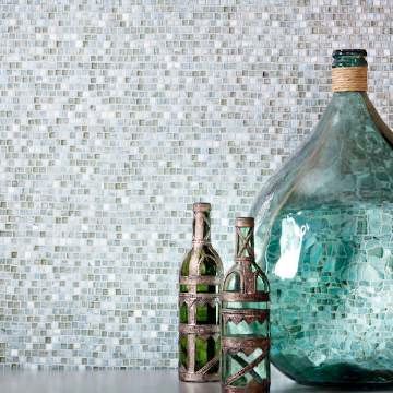 Two bottles of wine are sitting on a table in front of a mosaic wall.