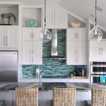 A kitchen with white cabinets , stainless steel appliances , and wicker chairs.