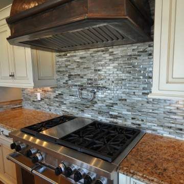 A kitchen with a stove top oven and a copper hood.