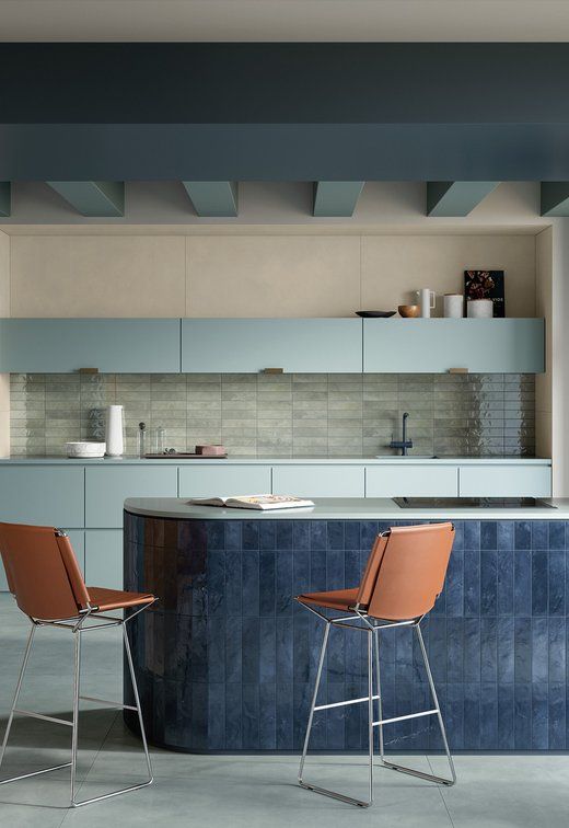 A kitchen with a blue island and two chairs