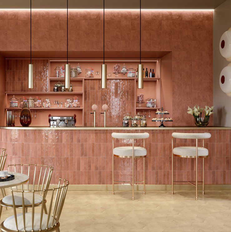 A kitchen with a counter , chairs , tables and shelves.