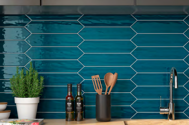 A kitchen counter with blue tiles and utensils on it.