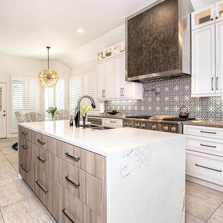 A kitchen with white cabinets and a large island in the middle.