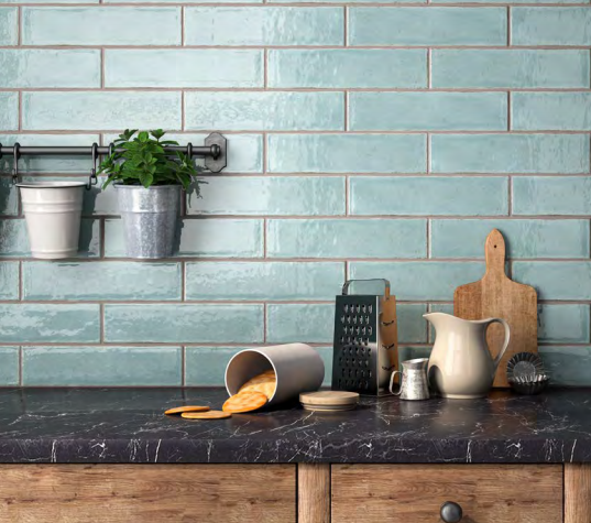 A kitchen counter with blue tiles and potted plants on it.