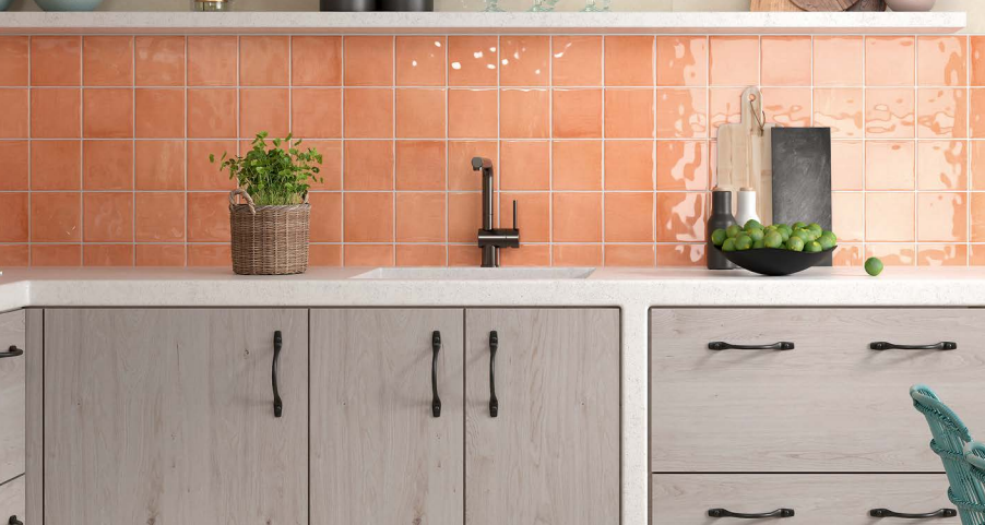 A kitchen with a sink , cabinets , shelves and coral tiles.
