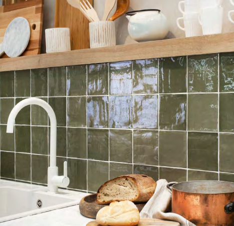 A kitchen with green tiles and a sink