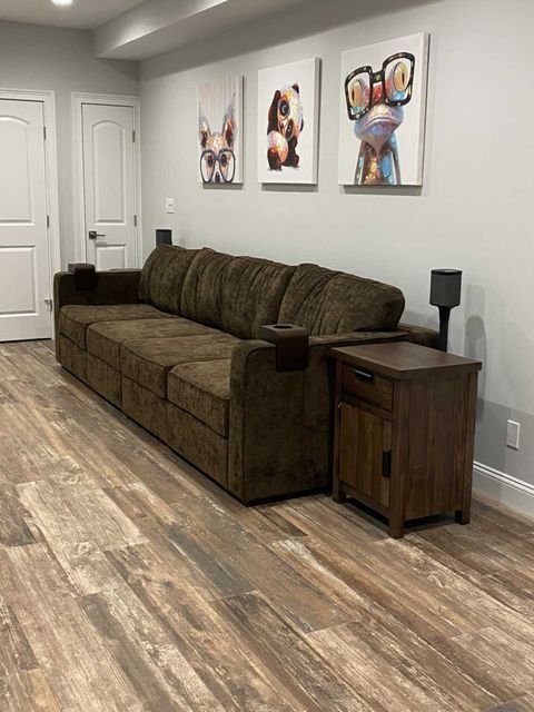 A living room with a couch , nightstand , and paintings on the wall.