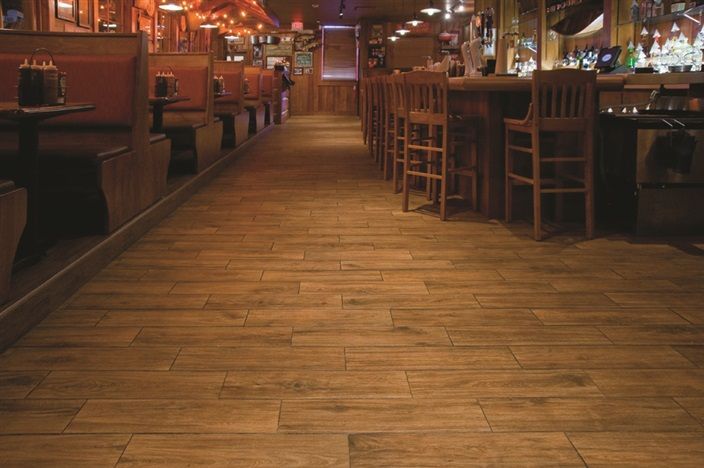 A long hallway in a restaurant with wooden floors and tables and chairs.