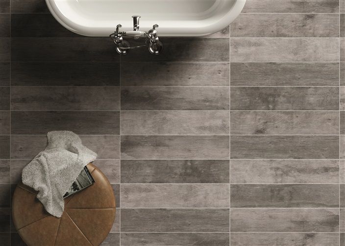 A bathroom with a bathtub and a stool with a towel on it.