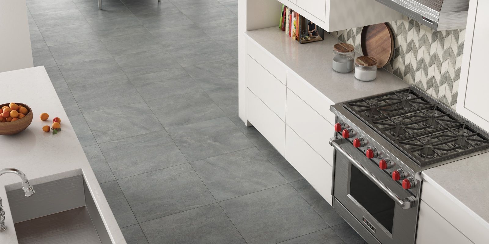 A kitchen with a stove and a bowl of fruit on the counter.