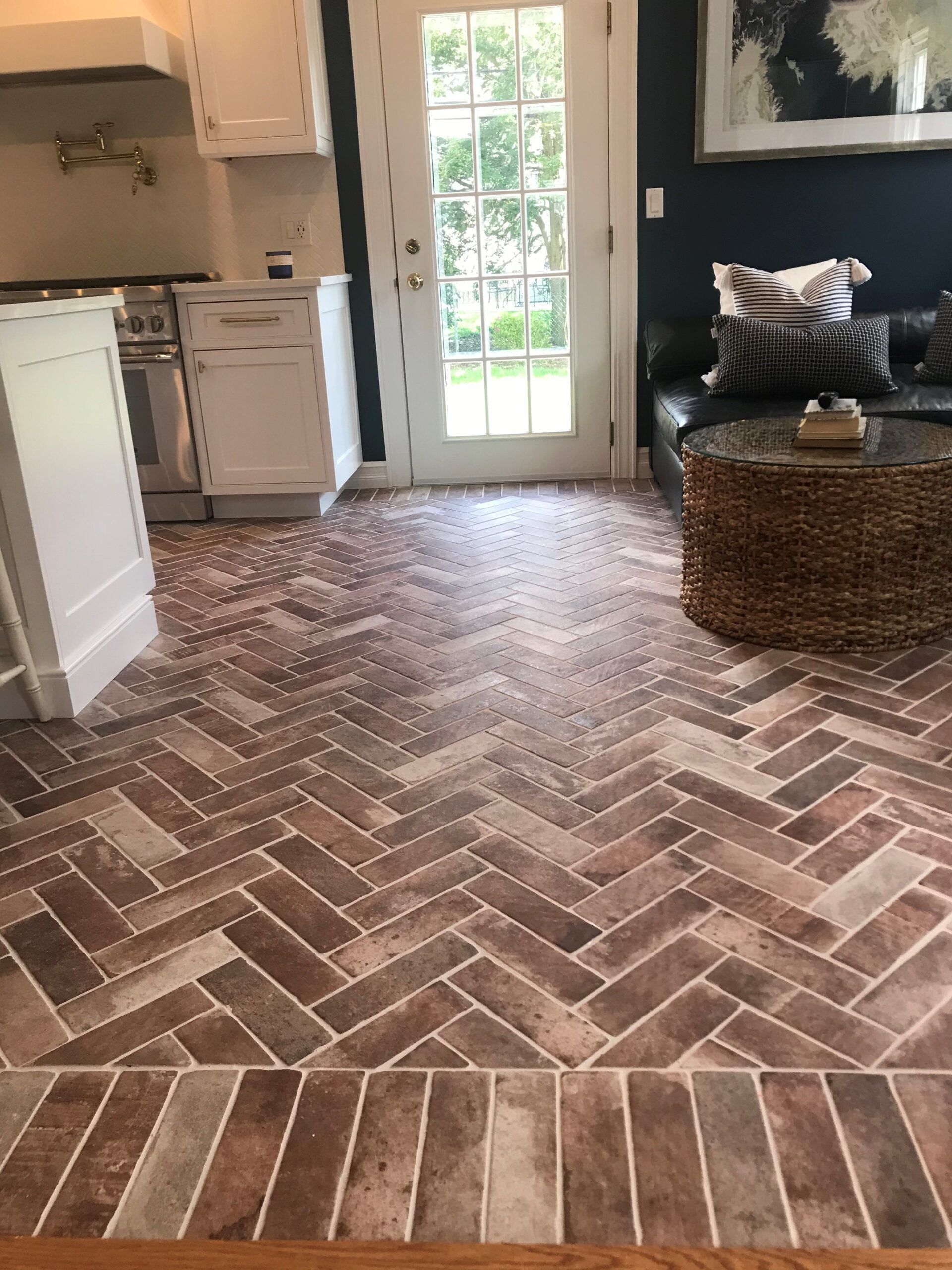 A living room with a herringbone tile floor and a couch.