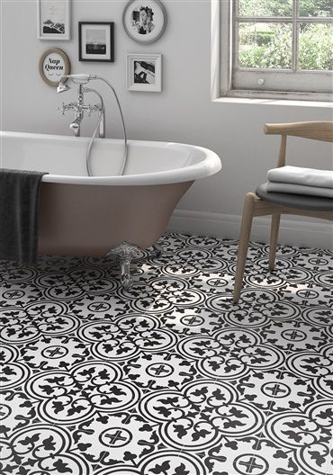 A bathroom with a bathtub , chair , and black and white tile floor.