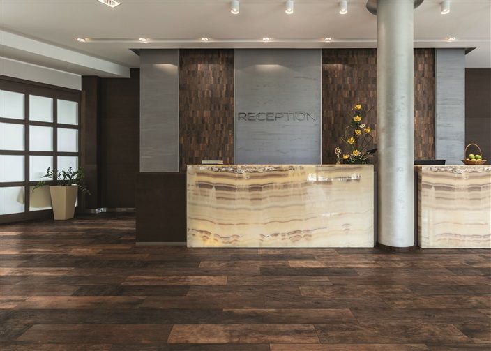 A hotel lobby with a reception desk and a wooden floor.