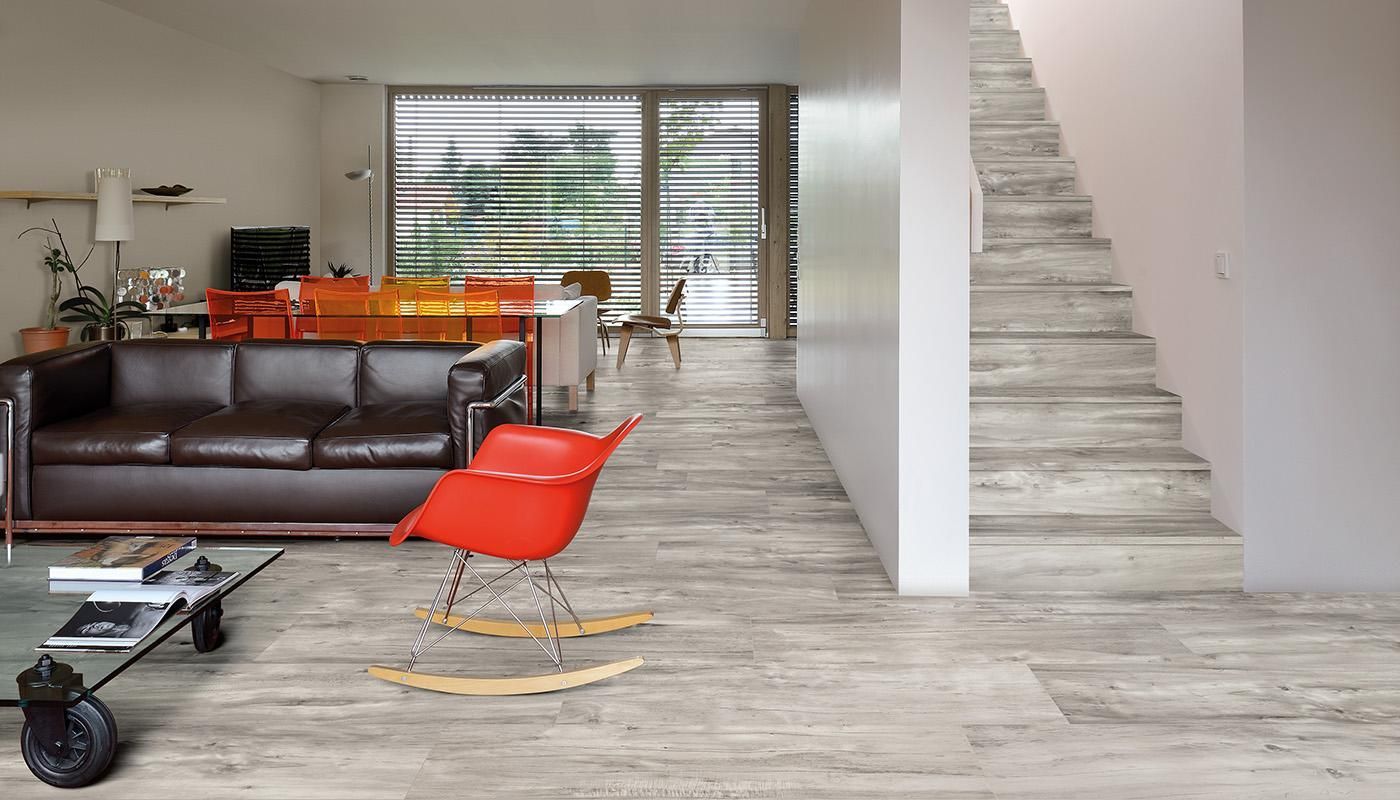 A living room with a couch , chair , table and stairs.