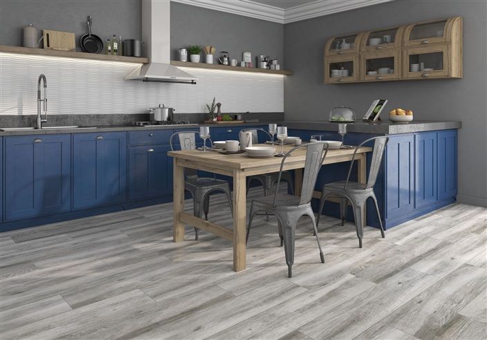 A kitchen with blue cabinets and a wooden table and chairs.