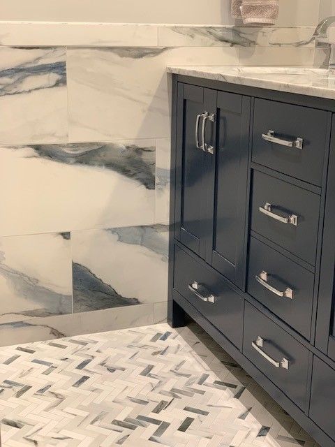 A bathroom with a blue vanity and white tiles.