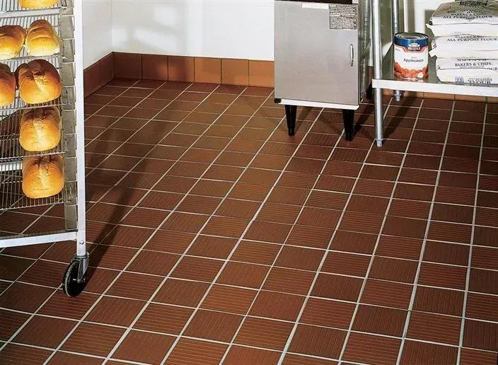 A bakery with brown tile floors and bread on racks.