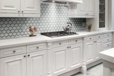 A kitchen with white cabinets and a stove top oven.