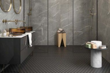 A bathroom with two sinks , a stool , and a walk in shower.