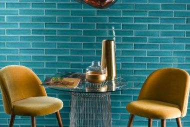 Two yellow chairs are sitting at a table in front of a blue brick wall.