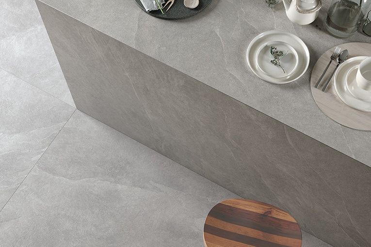 A kitchen counter with plates and silverware on it and a wooden stool.