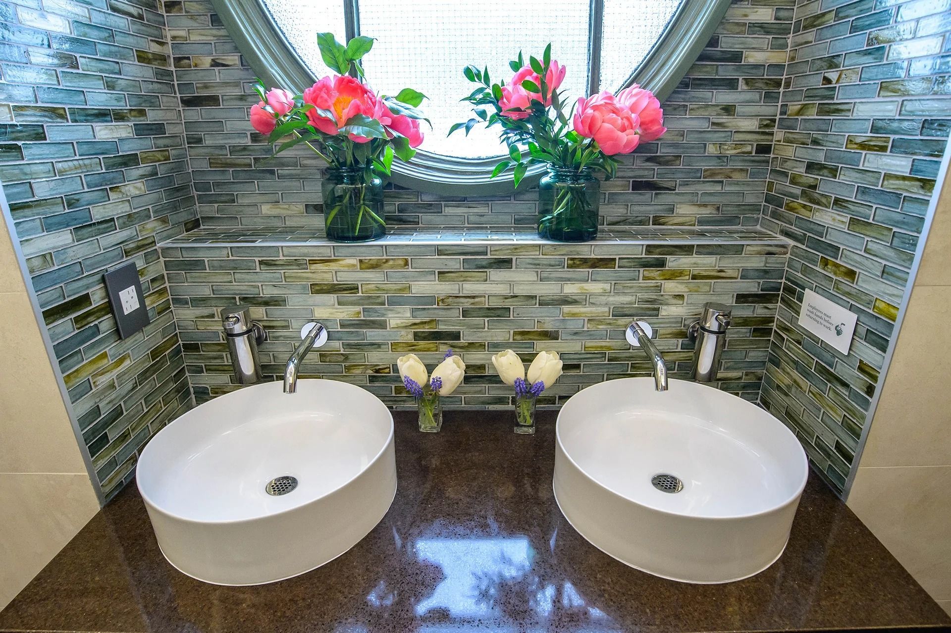 A bathroom with two sinks and flowers on the window sill