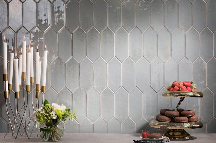 A table with a vase of flowers , candles , and a plate of donuts.