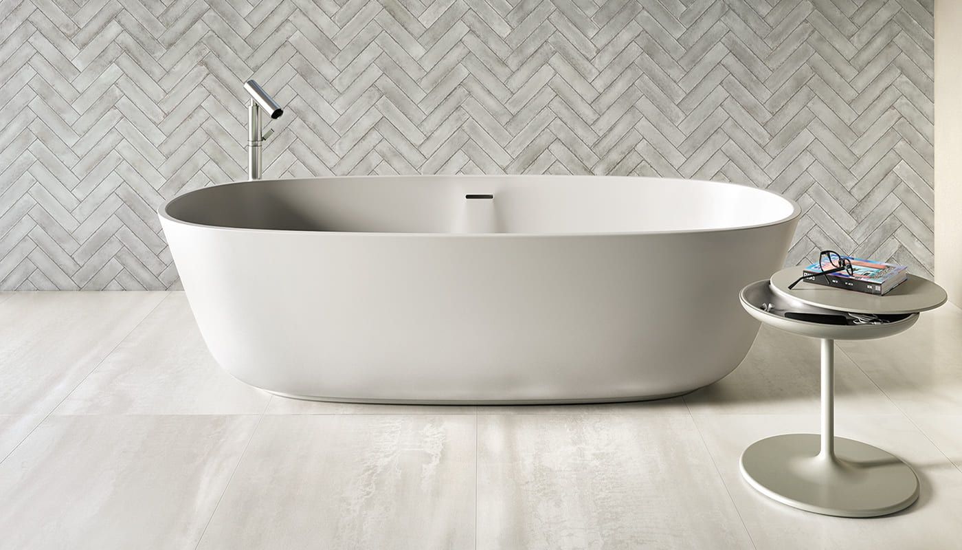 A white bathtub is sitting next to a small table in a bathroom.