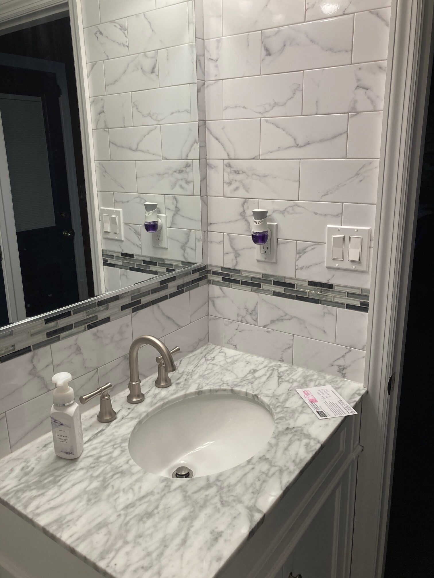 A bathroom sink with a marble counter top and a mirror.
