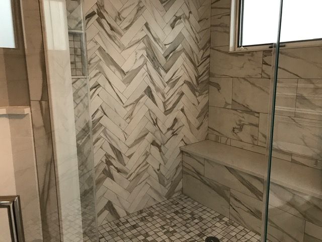 A shower with a chevron pattern on the wall and a glass door.
